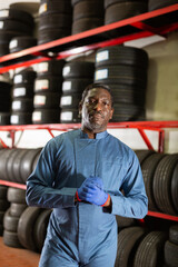 Fototapeta na wymiar Portrait of a serious auto mechanic in front of car tires