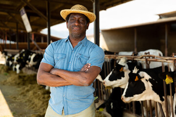 Successful african farmer man in strow hat posing at the modern cow farm