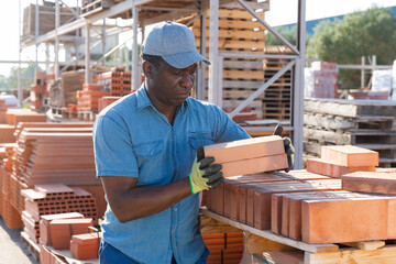 Construction shop worker stacks bricks on an open-air site