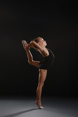 Little girl doing gymnastics on dark background