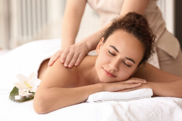 Fototapeta na wymiar Beautiful African-American woman getting massage by therapist in spa salon