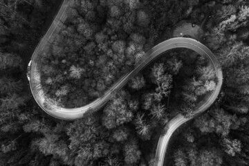Curvy road from above with lighttrails of driving cars in black and white.