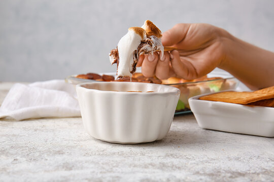 Woman Eating Tasty S'mores Dip At Light Table, Closeup