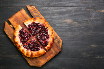 Board with tasty cherry khachapuri on wooden background