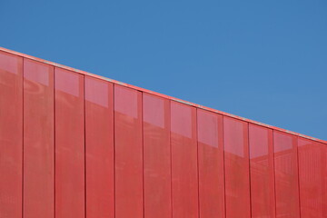Red metallic mesh decorative screen partition against blue sky
