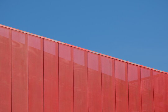 Red metallic mesh decorative screen partition against blue sky