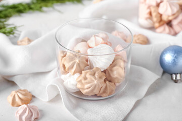 Glass bowl with tasty meringues on white background