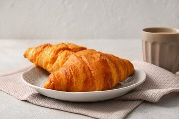 Plate with delicious croissants on white background