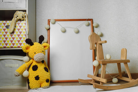 Mockup of the picture in the children's room. wooden horse and knitted toys. The interior of the nursery in beige colors.