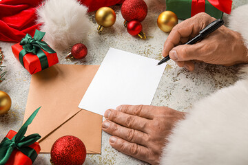 Santa Claus writing letter on light table with Christmas decor
