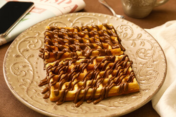 Plate of tasty Belgian Waffles with chocolate on table in cafe