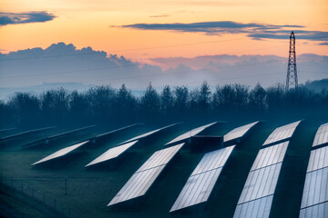 Solar energy park and conventional electricity pylon at sunset,Hampshire,England,UK.