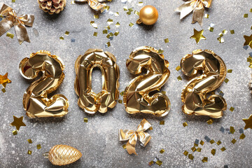 Golden balloons in shape of figure 2022 and Christmas decor on grunge background