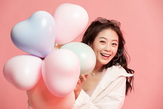 Studio shot of cute young woman with balloons