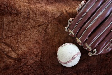 Baseball with leather glove on old brown background
