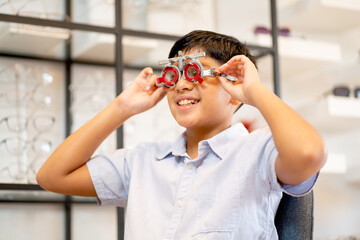 Boy has fun with special glasses that use for testing eyesight of customer in optical shop.