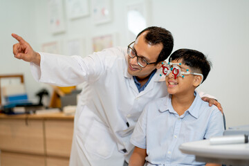 Ophthalmologist or optical staff point to the direction for viewing of Indian boy who wear special...