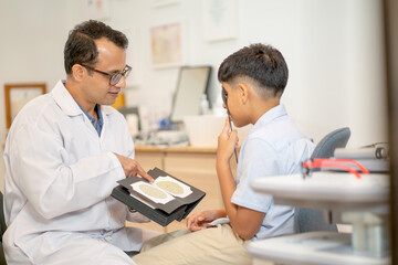 Obraz na płótnie Canvas Ophthalmologist or optical staff use book of color blindness test with Indian boy to test for continue the process in optical shop.