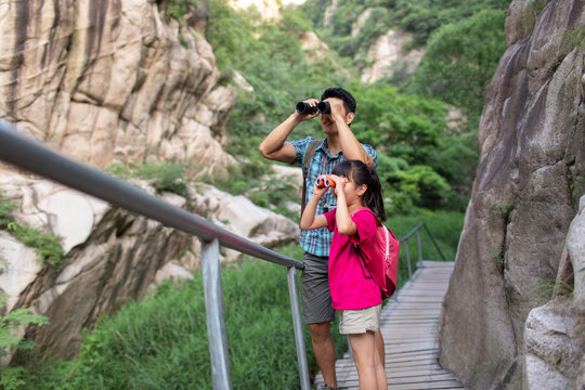 Happy young father and daughter using binoculars outdoors