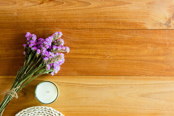 Fototapeta premium A purple flowers on wooden background with candles. 