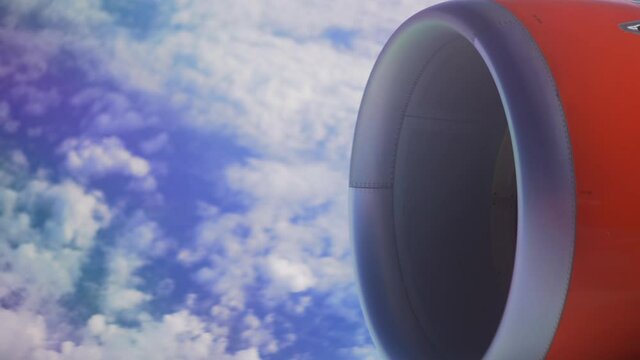 Plane engine, view from a plane window while flying over a blue sky filled with light clouds, peaceful holiday trip