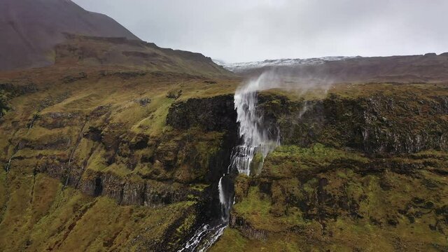 Drone flight towards wind-blown waterfall in Iceland