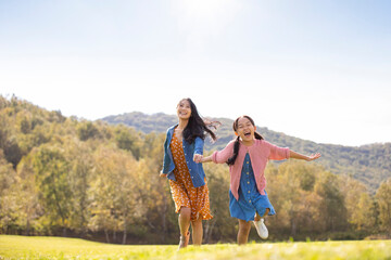 Happy Chinese mother and daughter playing on meadow