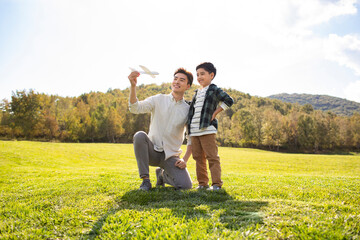Happy Chinese father and son playing on meadow
