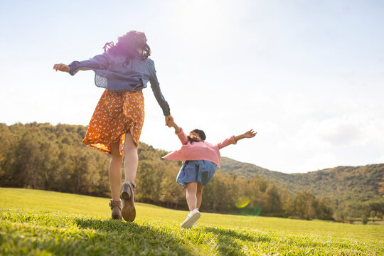 Happy Chinese mother and daughter playing on meadow