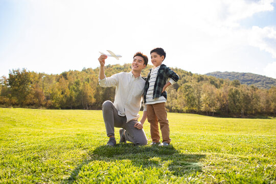 Happy Chinese father and son playing on meadow