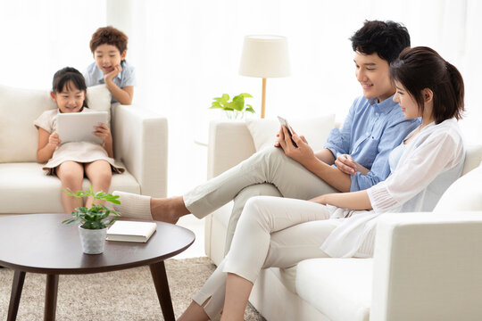 Happy family using digital devices on sofa