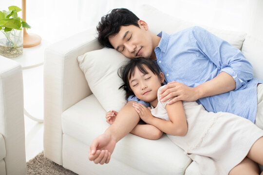 Cheerful father and daughter resting on sofa