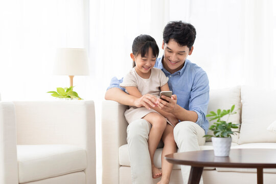 Cheerful father and daughter using smart phone
