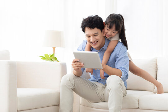 Cheerful father and daughter using digital tablet