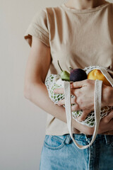 The girl is holding an eco-aware handbag full of fruits.