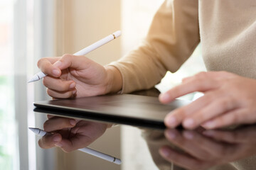 Young business woman hand holding stylus pen work with digital tablet computer at modern home office.
