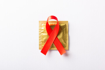 Red bow ribbon symbol HIV, AIDS cancer awareness and condom with shadows, studio shot isolated on...