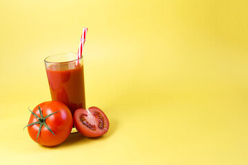 Advertising tomato juice. Tomato juice with a red tube and red tomatoes on a bright yellow background