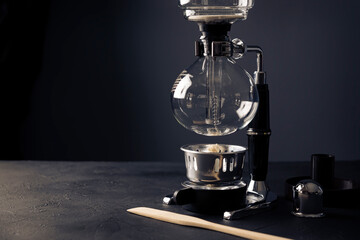 Vacuum coffee maker also known as vac pot, siphon or syphon coffee maker on rustic black stone table. Copy space for your text