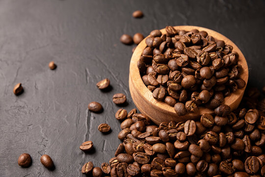 Organic toasted coffee beans on rustic black stone table with copy space for your text. Close up image