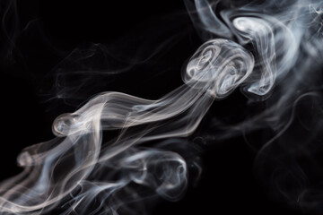 Abstract background of chaotically mixing puffs of smoke on dark background. Concept of alternative non-nicotine smoking. Color smoke on dark background. E-cigarette. Blurry image, soft focus. Vaping