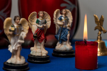 three statuettes of angels in a row next to a lighted candle