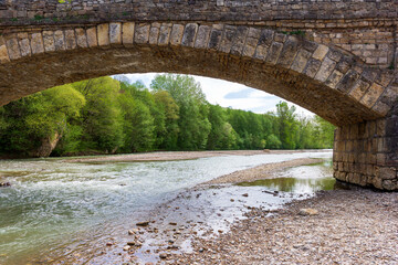 Stone bridge,park area along the bed of a mountain river ,walking on a sunny summer day.