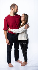dad hugs daughter by the shoulders in the studio. a man in a burgundy-red T-shirt, a girl in a white sweatshirt. isolated white background