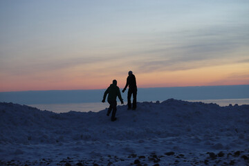 People on the ice at the beach in the winter. 