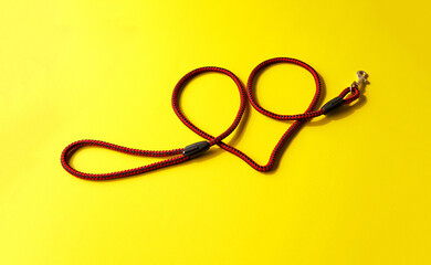 Heart shaped dog leash placed on a yellow background. Isolated.
