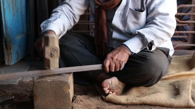 Barefoot welder at work with hammer and iron bar in Sakhi Saheli village, Rajasthan. Handheld
