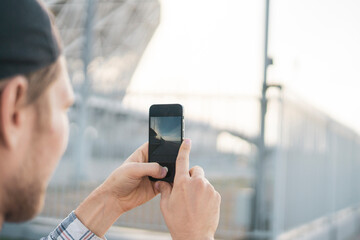 young male person tourist with smartphone taking a photo of city scene