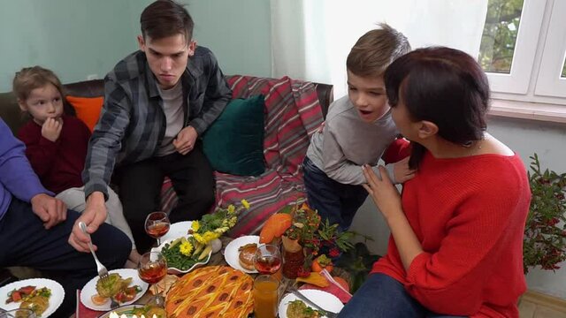 The Jewish holiday of Hanukkah. Father, mother and children have a fun dinner together. Traditional kosher food and drinks on the festive table