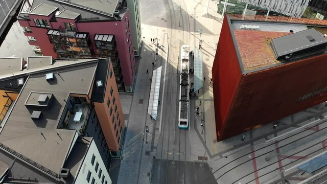 Public tramway stopping at station near downtown buildings in Gothenburg, aerial view